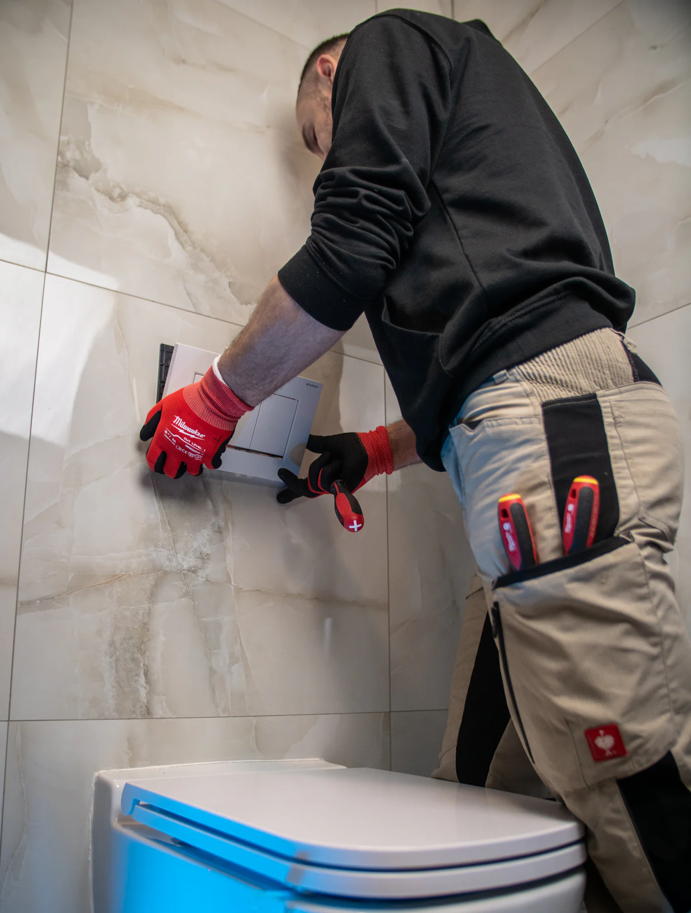 Instalator cu mănuși de protecție lucrând la o instalație sanitară